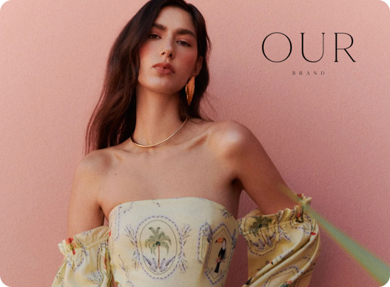 Woman wearing a strapless dress with embroidery against a pink background, featuring 'OUR' brand.